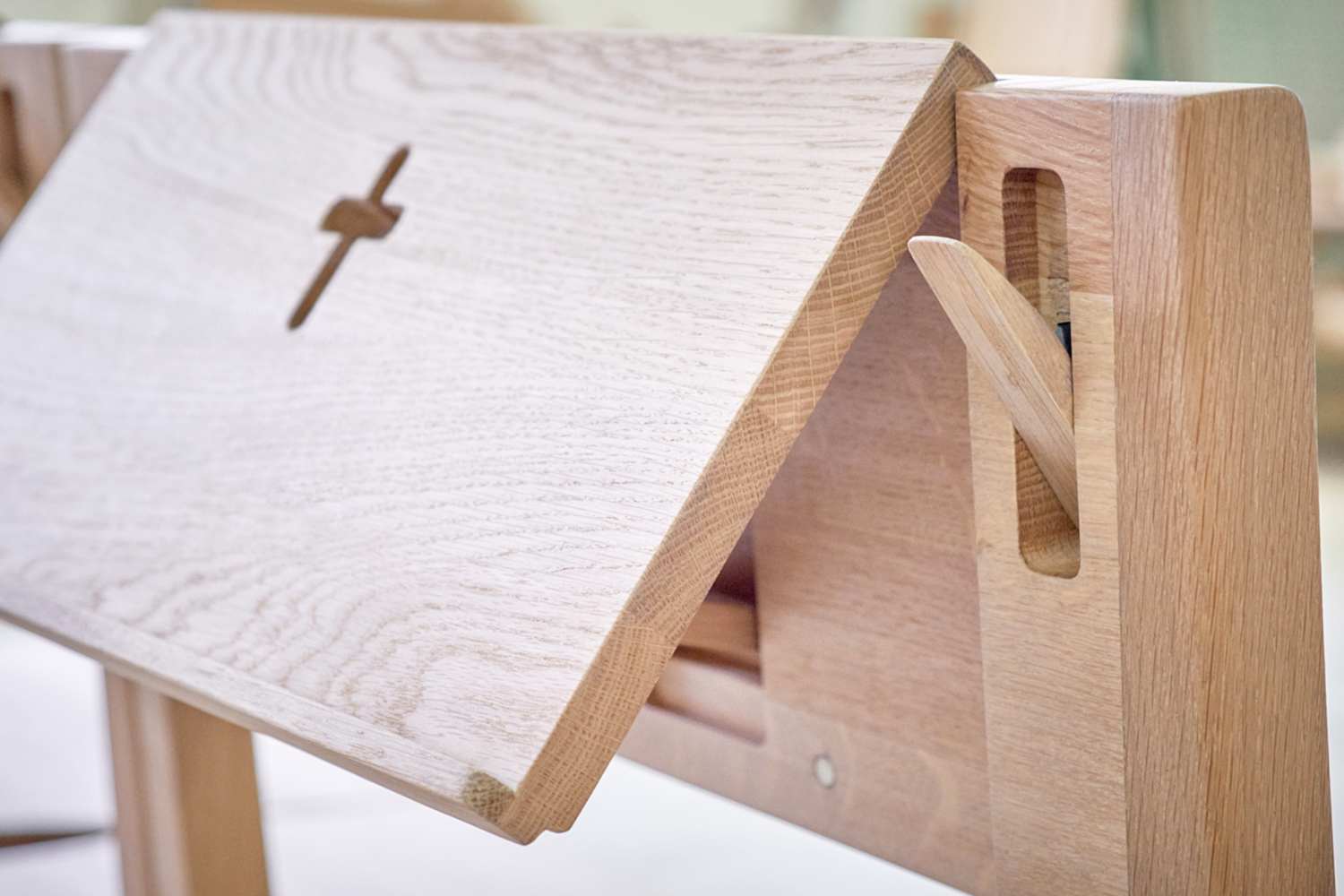 Kirchenstuhl ZOE aus Eichenholz, der mit dem Kreuz aus Eichenholz verbunden wird mit einem einziehbaren Bibelhalter und Taschenhalter.